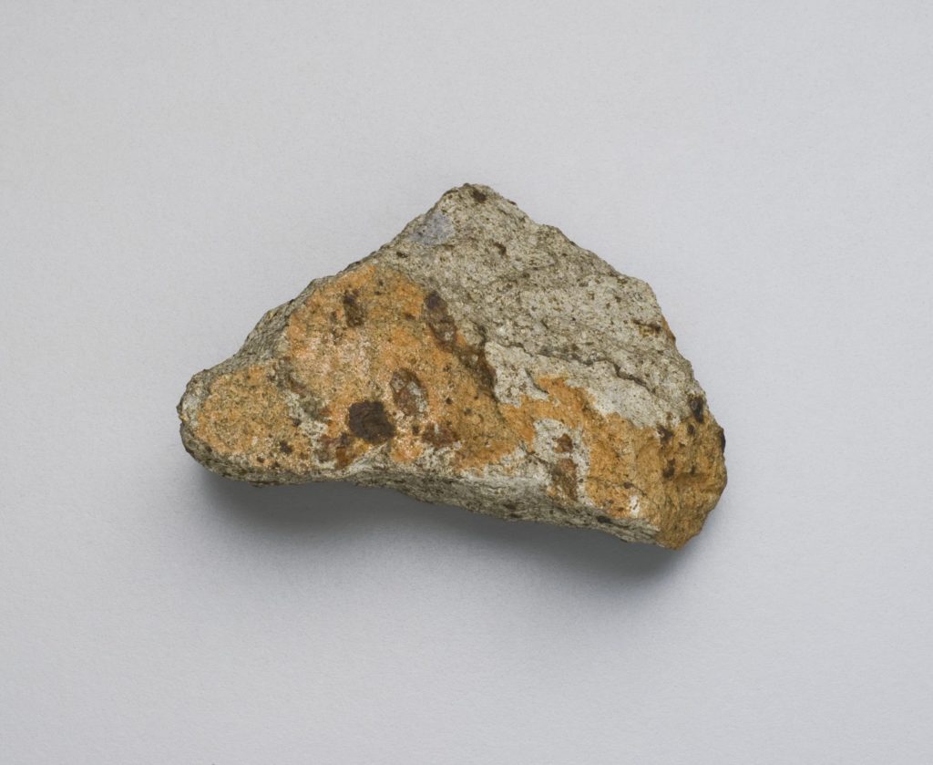 A photograph of a brown and grey stone against a grey background.